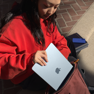 Une étudiante range un MacBook Air dans son sac à dos